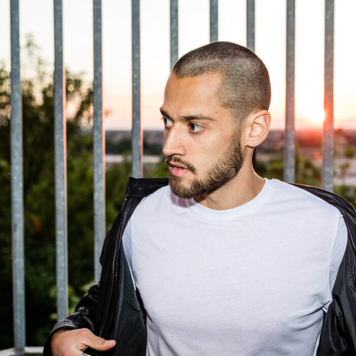 Bei Sonnenuntergang steht FINN vor einem Gitter und schaut zur Seite