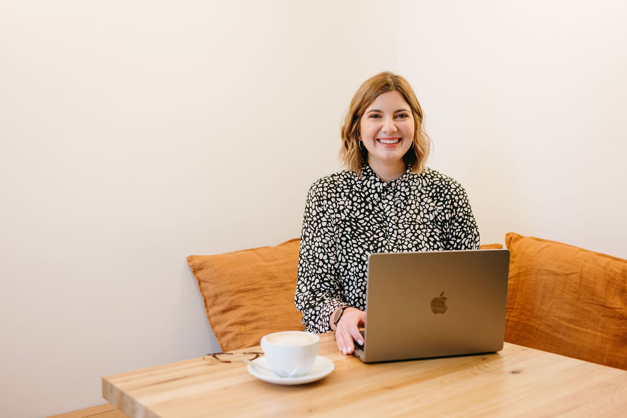 Fotografin Laura-Sophie Jung sitzt mit Laptop und Kaffee am Tisch