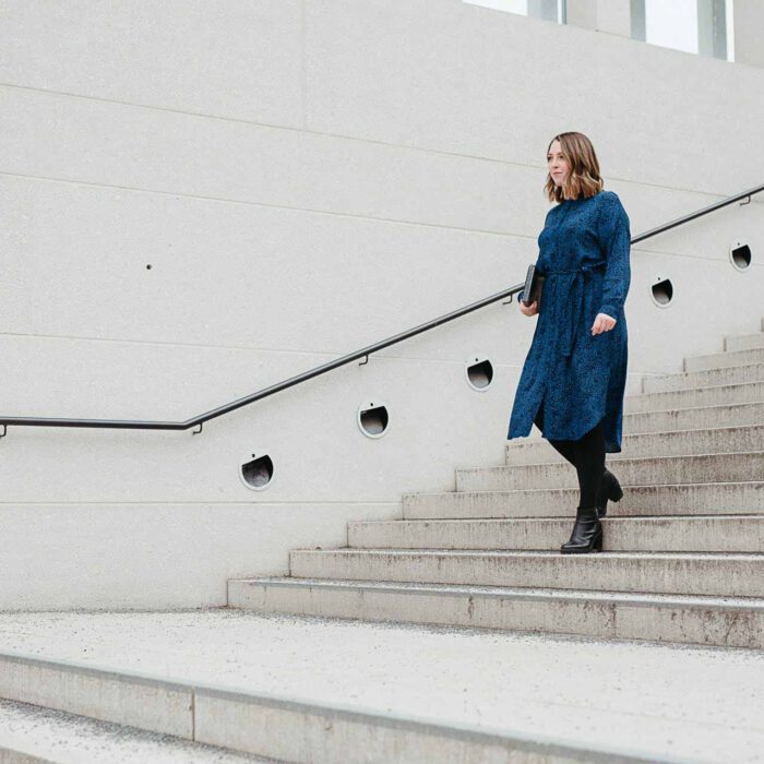 Frau läuft mit Notitzbuch im Arm die Treppe herunter