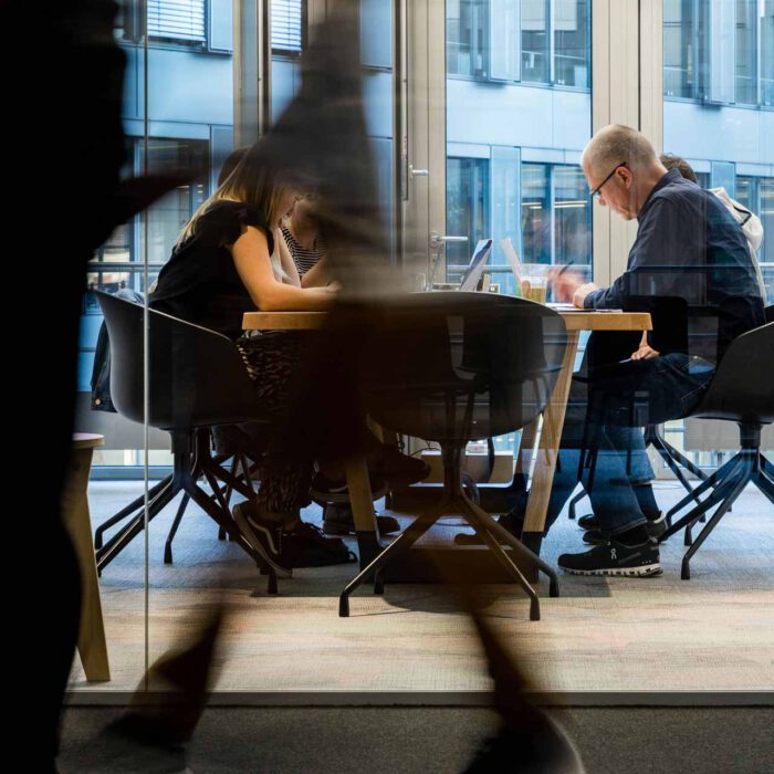 Einblick in Konferenzraum. Im Vordergrund laufen Menschen